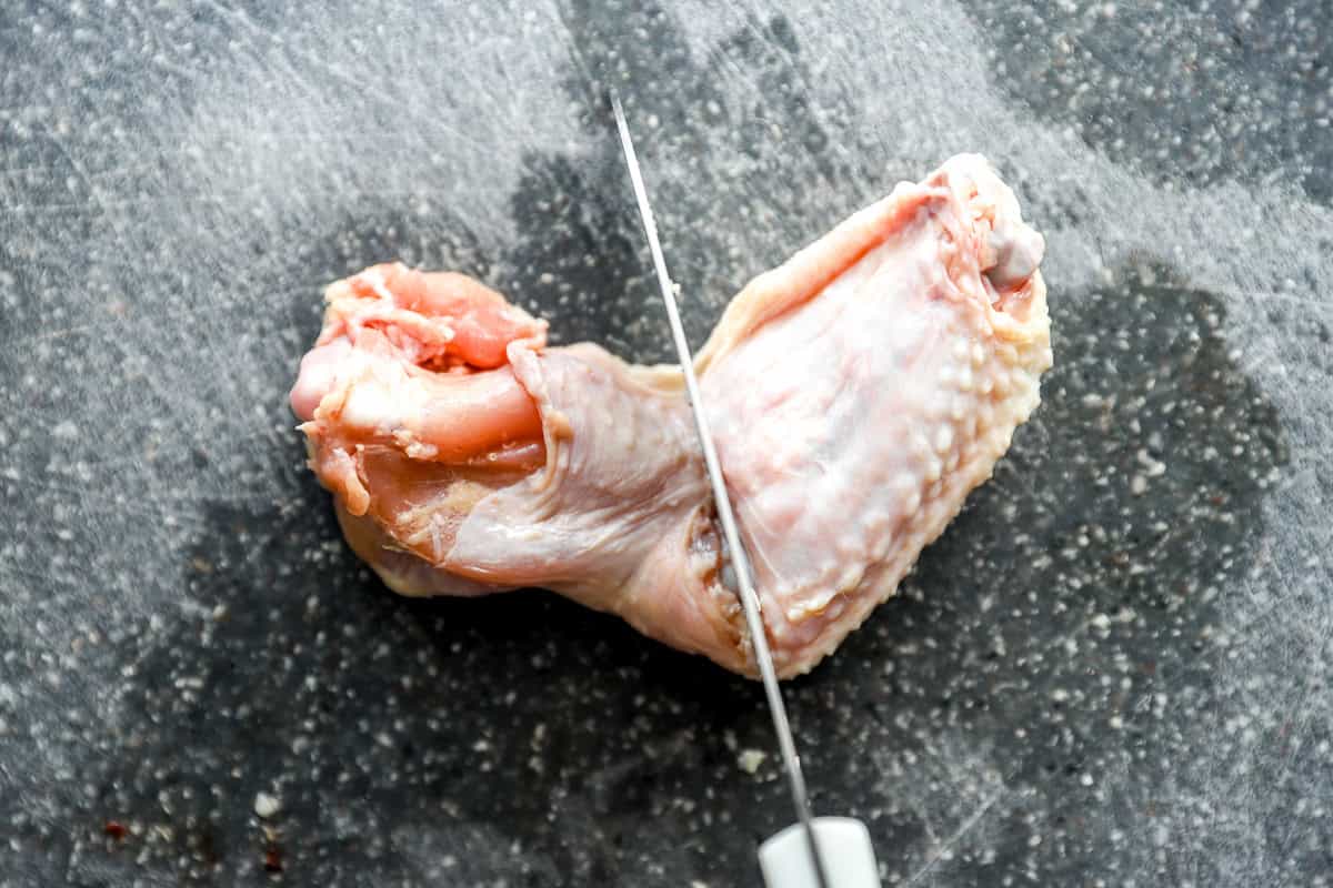 a knife cutting the joint between a wing flat and drumette.