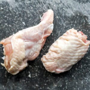 a raw wing flat and drumstick on a cutting board.