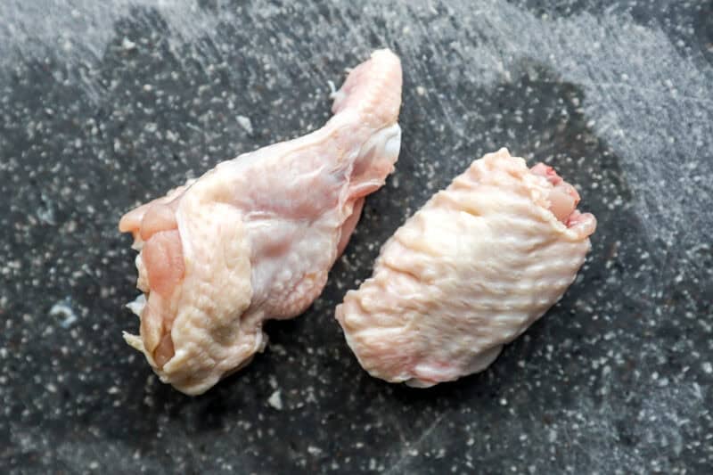 a raw wing flat and drumstick on a cutting board.
