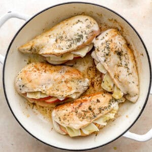 seared apple brie stuffed chicken breasts in a pan.