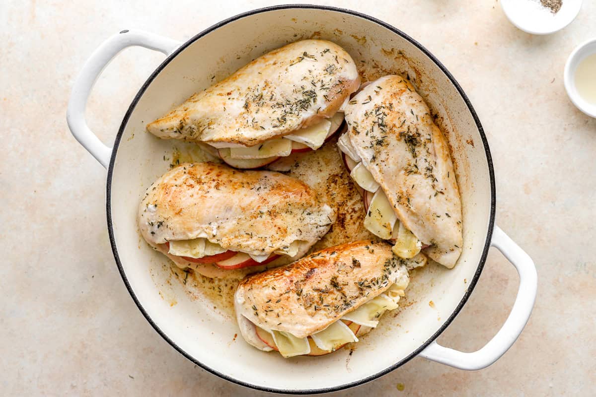 seared apple brie stuffed chicken breasts in a pan.