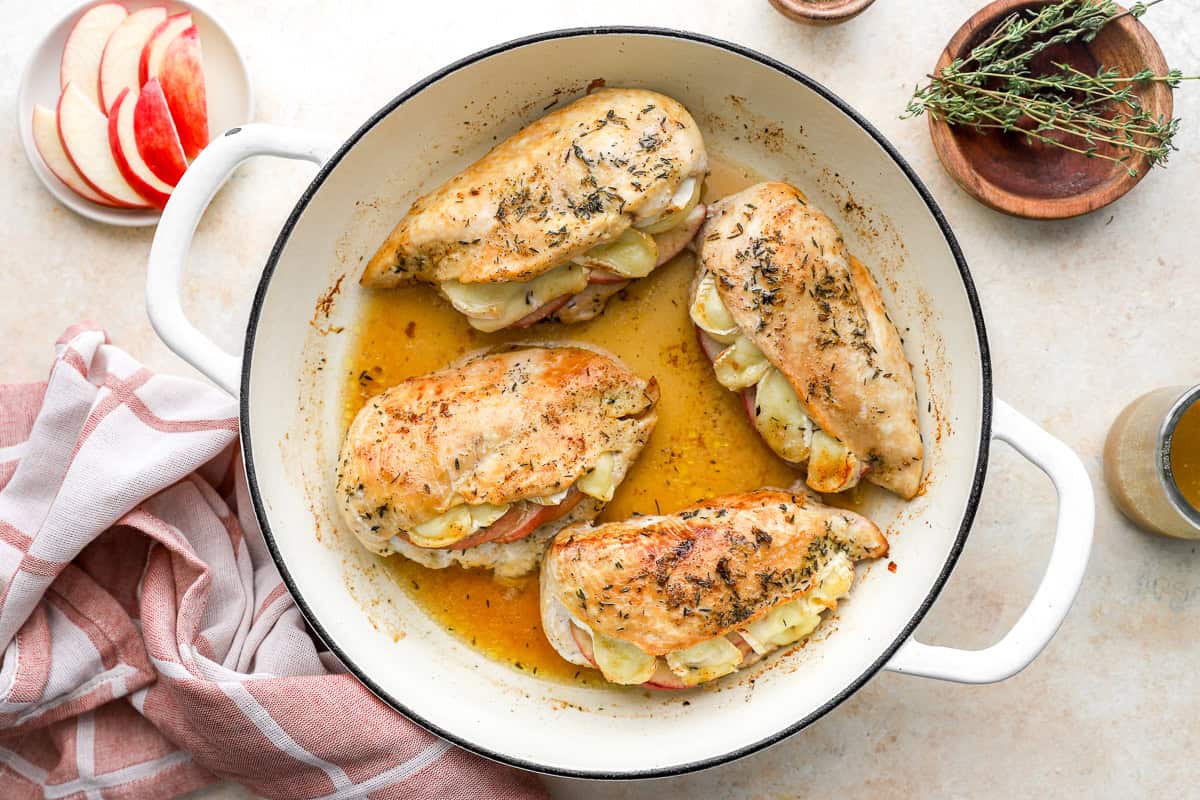 overhead view of saucy apple brie stuffed chicken breasts in a pan.