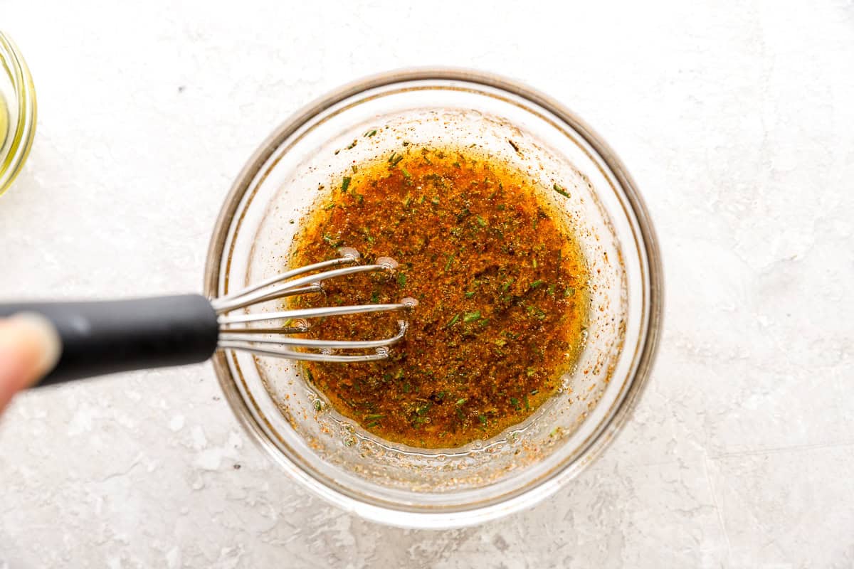 seasoned oil in a glass bowl with a whisk.