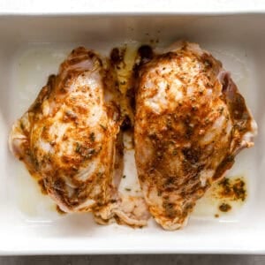 seasoned raw split chicken breasts in a baking dish.