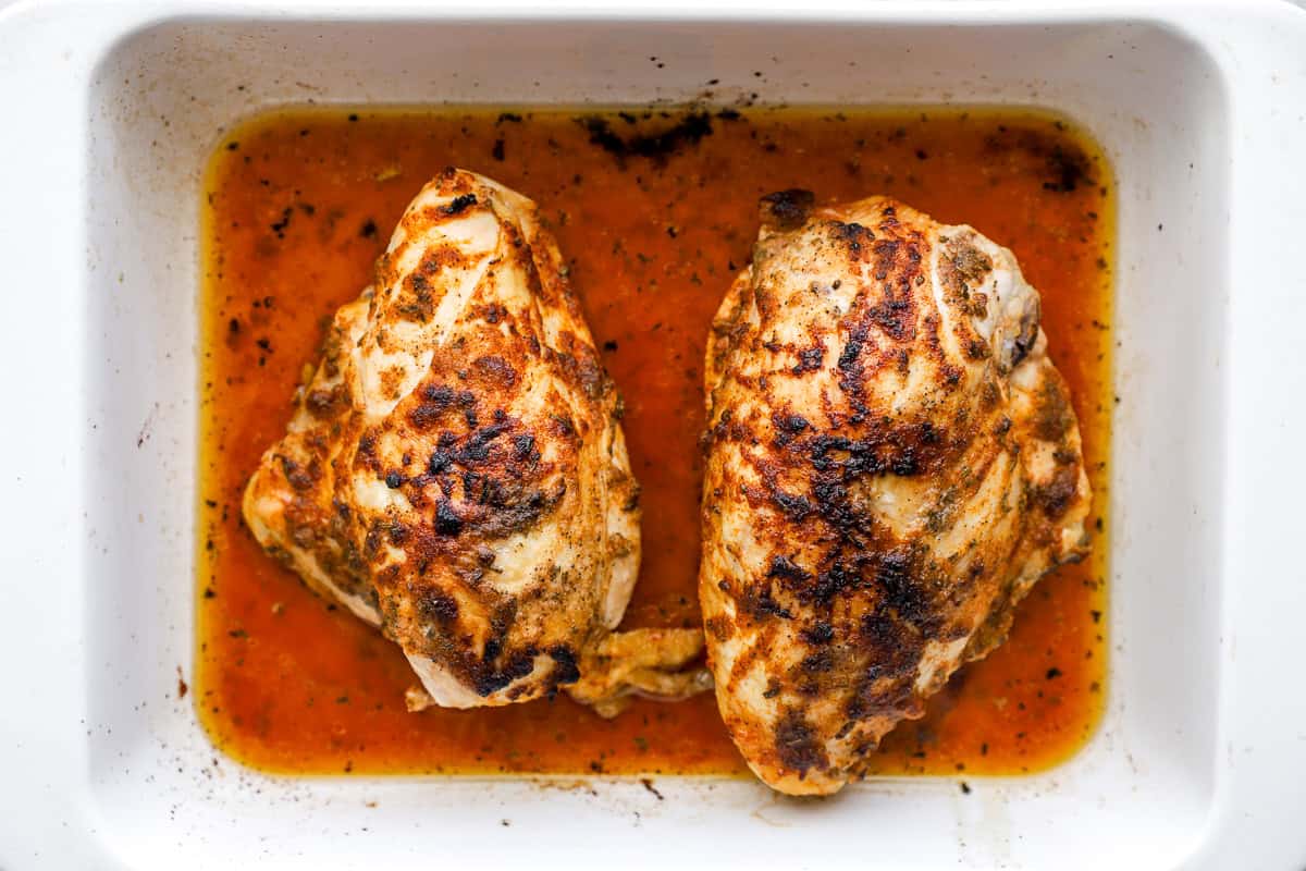 seasoned baked bone in chicken breasts in a baking dish.