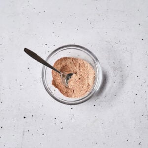 a mix of spices and seasonings in a glass bowl with a spoon.