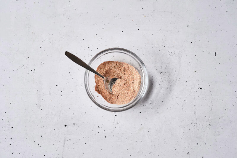 a mix of spices and seasonings in a glass bowl with a spoon.