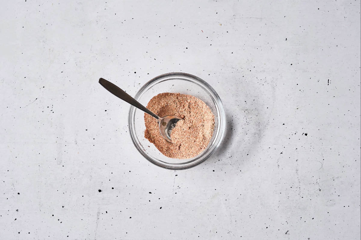 a mix of spices and seasonings in a glass bowl with a spoon.