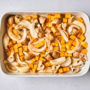 tossed seasoned thick-sliced onion, quartered mushrooms, and cubed butternut squash in a baking dish.