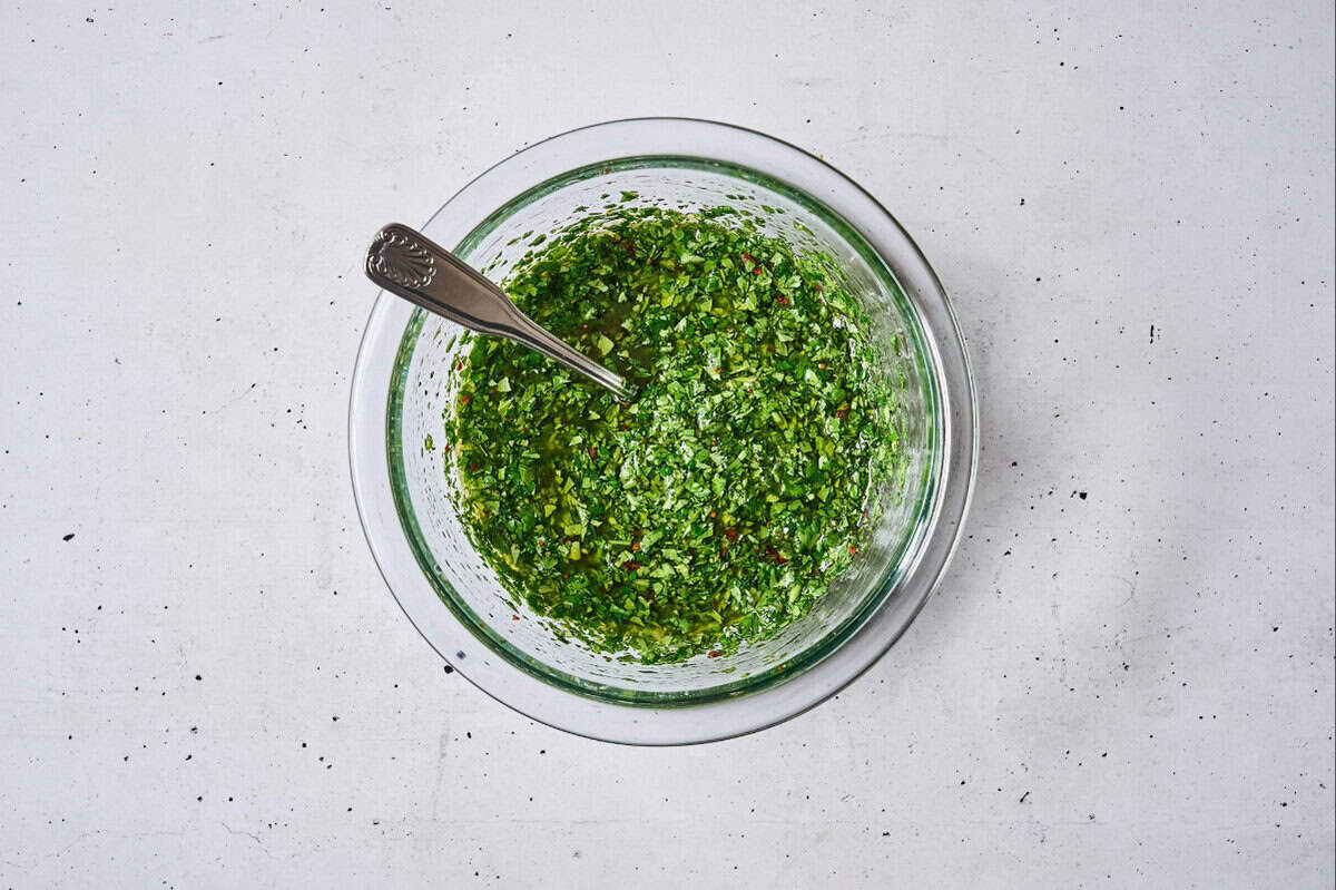 chimichurri sauce in a glass bowl with a spoon.