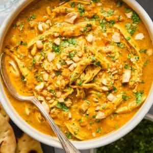 overhead view of a bowl of chicken mulligatawny soup with a spoon.