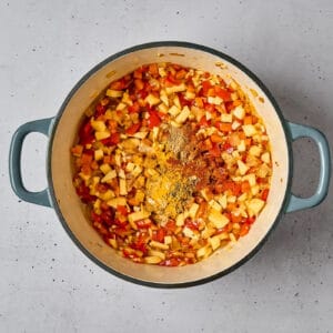 adding spices to sautéed vegetables in a dutch oven.