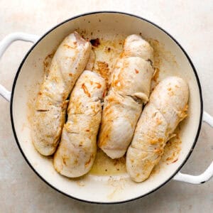 four chicken roulades searing in an oven-safe pan.
