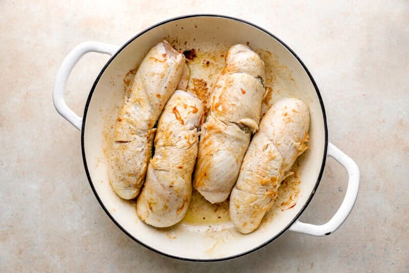 four chicken roulades searing in an oven-safe pan.