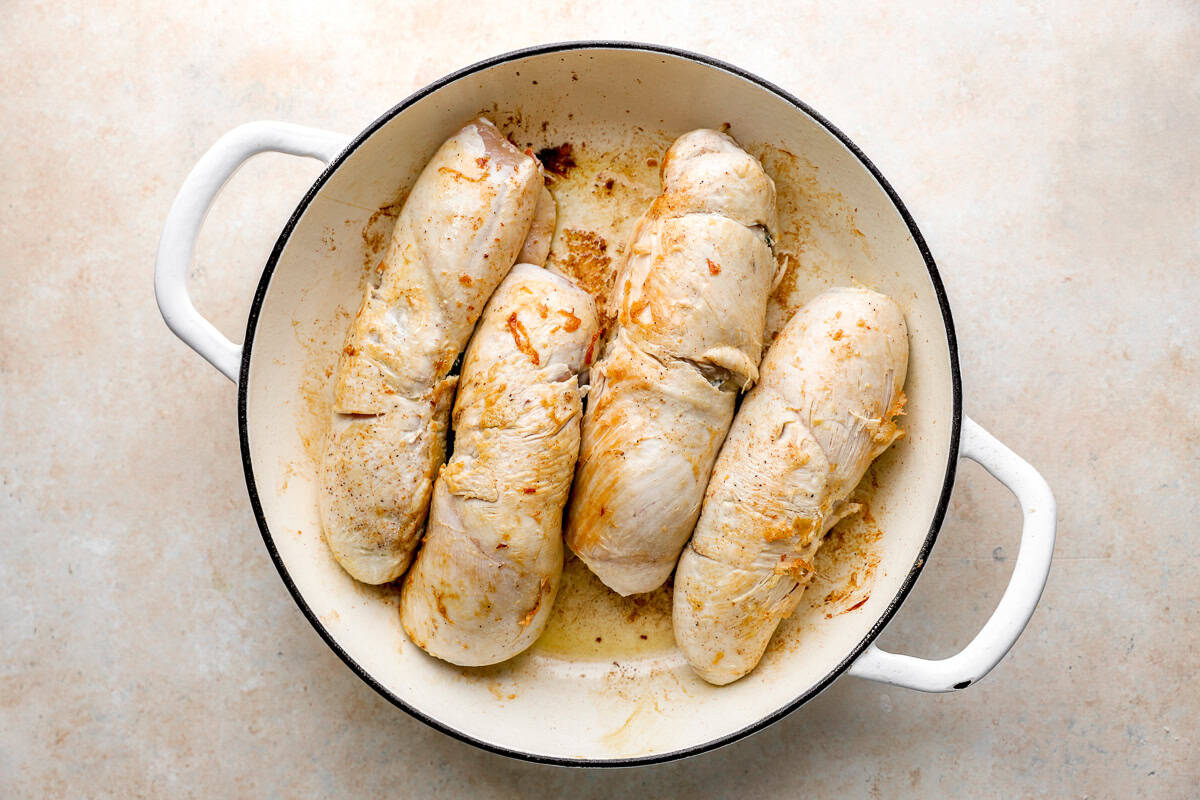 four chicken roulades searing in an oven-safe pan.