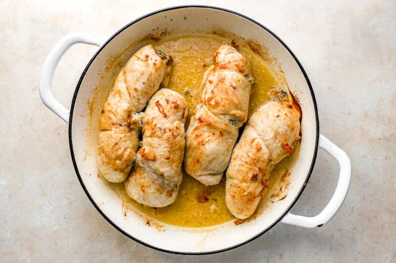 four roasted chicken roulades in an oven-safe pan.