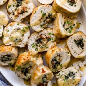 closeup view of sliced chicken roulades on a serving dish drizzled with gravy.