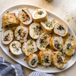 overhead view of sliced chicken roulades on a serving dish drizzled with gravy.