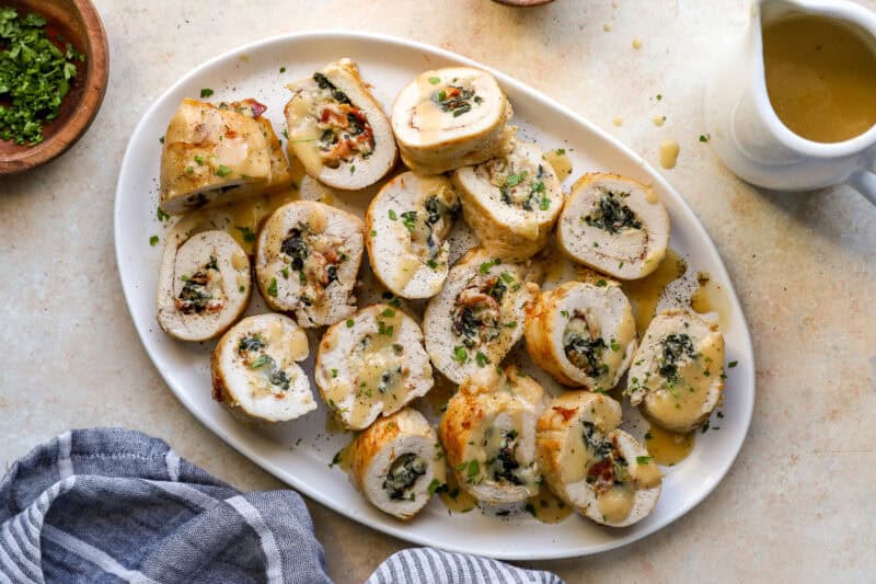 overhead view of sliced chicken roulades on a serving dish drizzled with gravy.