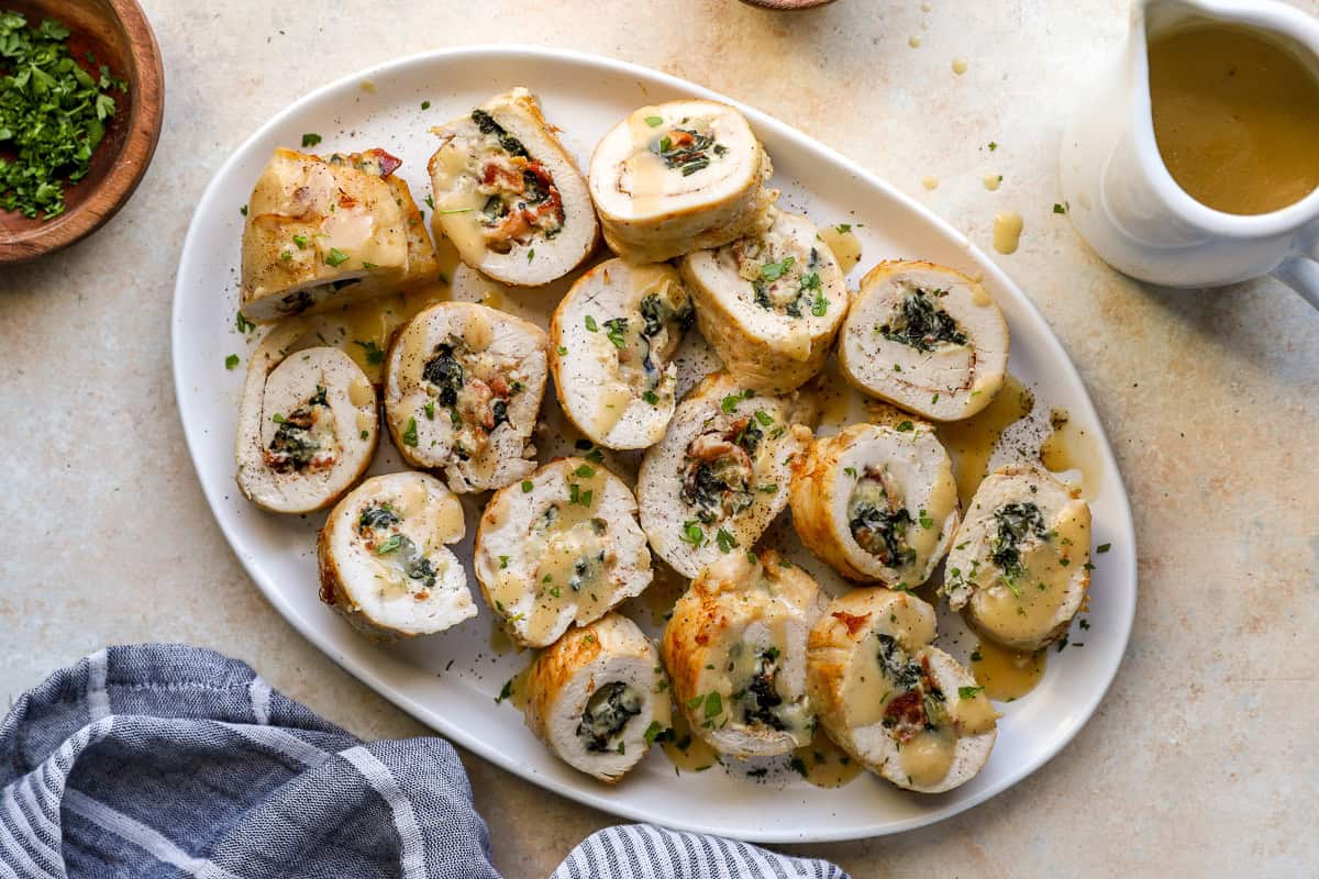 overhead view of sliced chicken roulades on a serving dish drizzled with gravy.