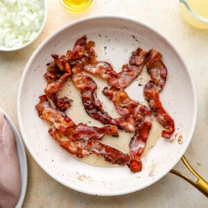 frying bacon slices in a frying pan.