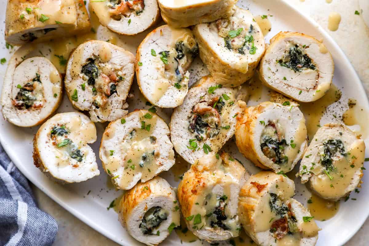 closeup overhead view of sliced chicken roulades on a serving dish drizzled with gravy.