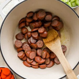 sauteeing chicken sausage rounds in a pot.