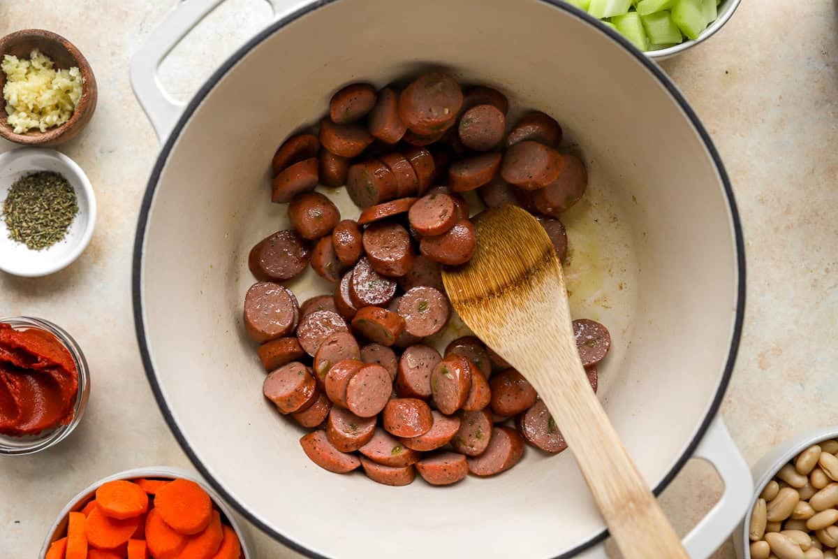sauteeing chicken sausage rounds in a pot.