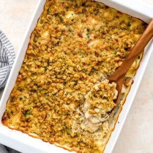 overhead view of baked chicken and stuffing casserole in a baking dish with a wooden spoon.