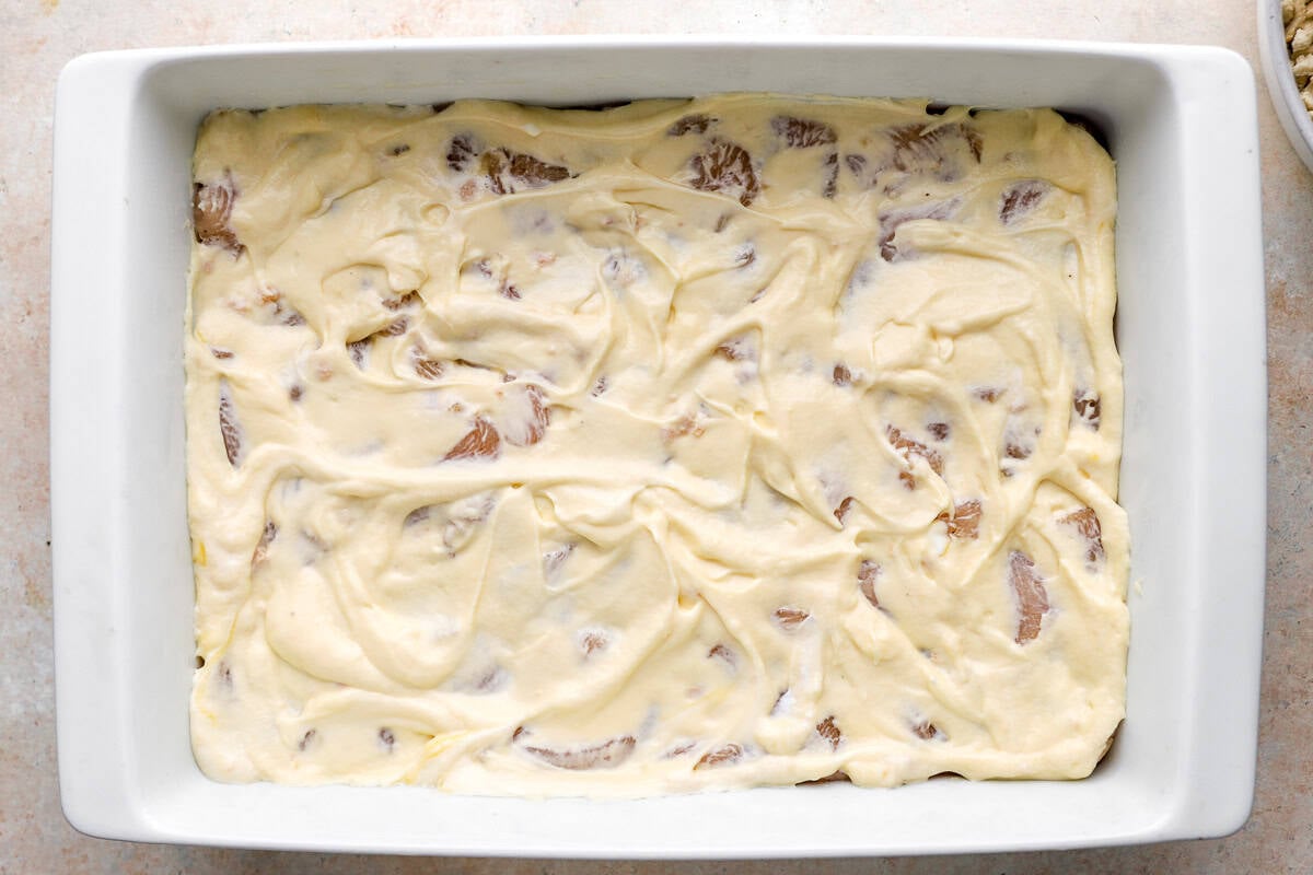 cream of chicken soup mixture poured evenly over raw seasoned chicken pieces in a casserole dish.