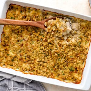 baked chicken stuffing casserole with a wooden spoon in a casserole dish.