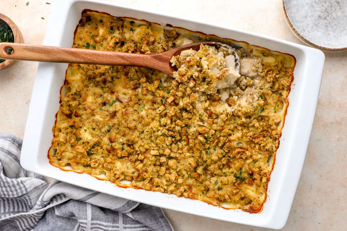 baked chicken stuffing casserole with a wooden spoon in a casserole dish.