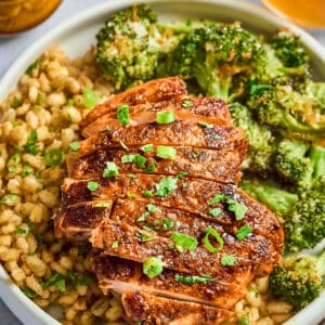 a sliced chipotle orange chicken thigh over couscous with broccoli.