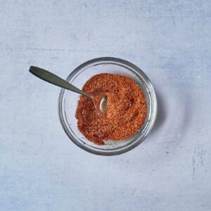 spice mix in a glass bowl with a spoon.