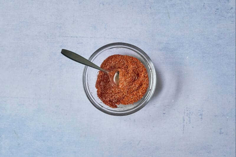 spice mix in a glass bowl with a spoon.