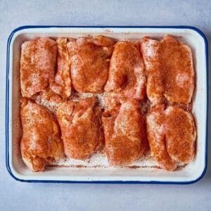 seasoned raw chicken thighs in a baking dish.