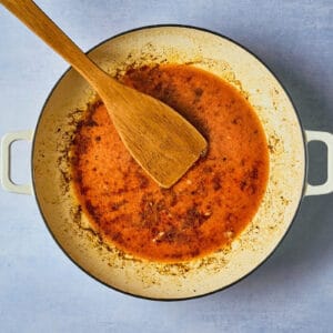 chipotle orange sauce in a dutch oven with a wooden spoon.