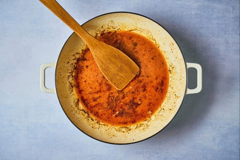 chipotle orange sauce in a dutch oven with a wooden spoon.