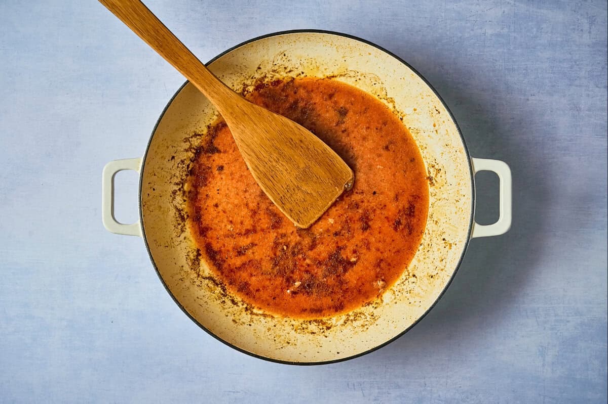 Honey orange sauce in a dutch oven with a wooden spoon.