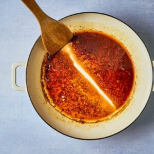 dragging a wooden spoon through reduced chipotle orange sauce to leave a line.