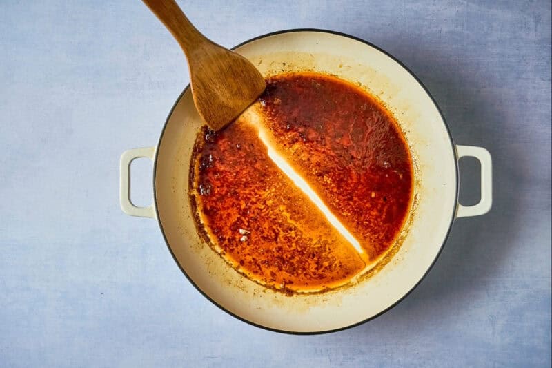 dragging a wooden spoon through reduced chipotle orange sauce to leave a line.