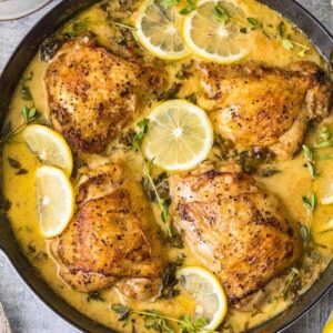 Lemon Butter Chicken with creamy sauce cooked in a skillet.