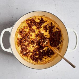 sauteed onion, garlic, and spices in a dutch oven with a wooden spoon.