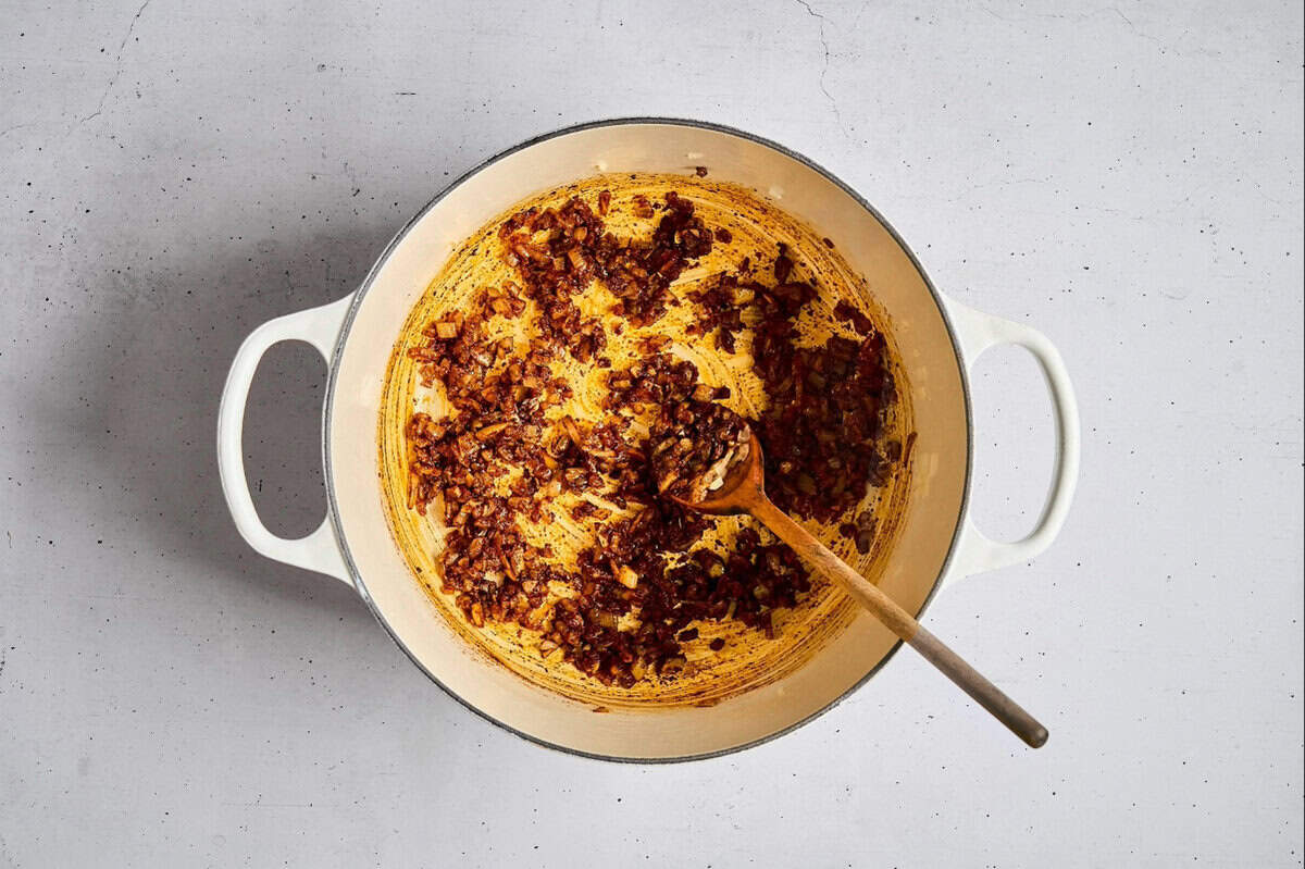 sauteed onion, garlic, and spices in a dutch oven with a wooden spoon.
