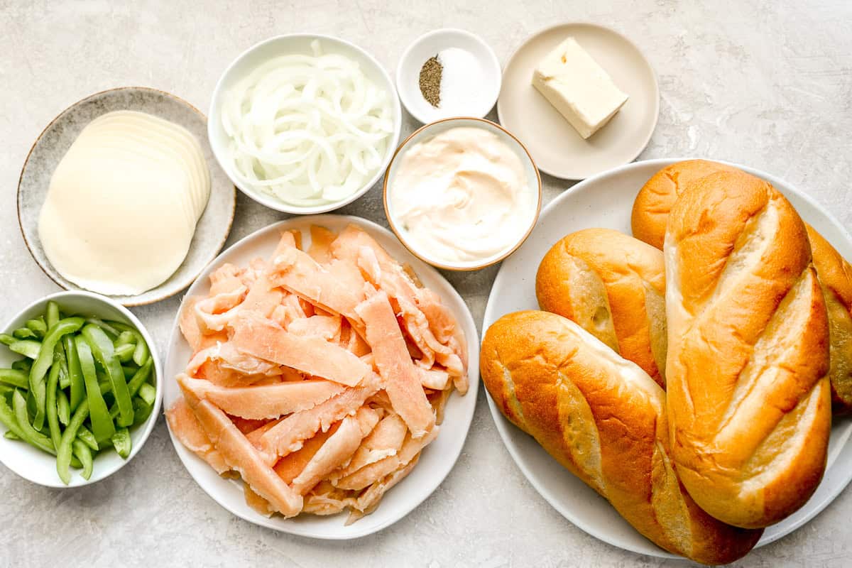 portioned ingredients for chicken cheesesteak on individual plates.