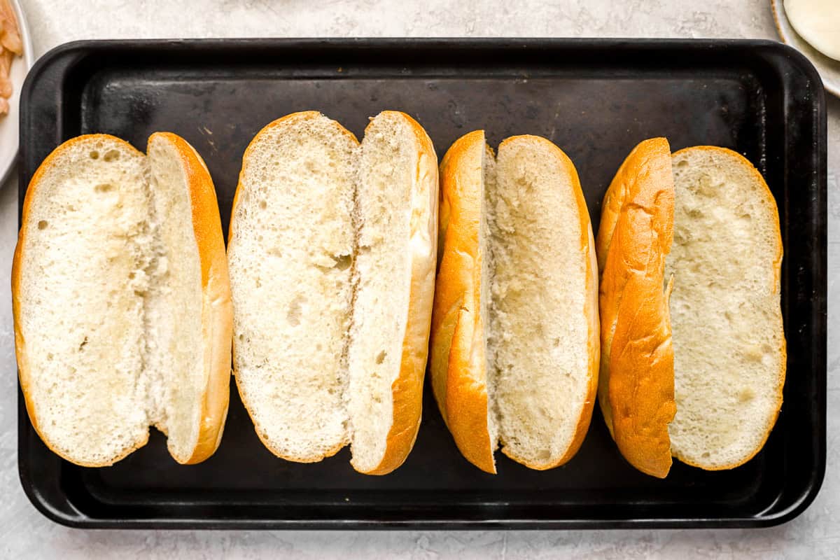 four buttered hoagie rolls on a grill pan.