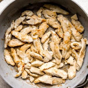 searing sliced chicken in a pan.