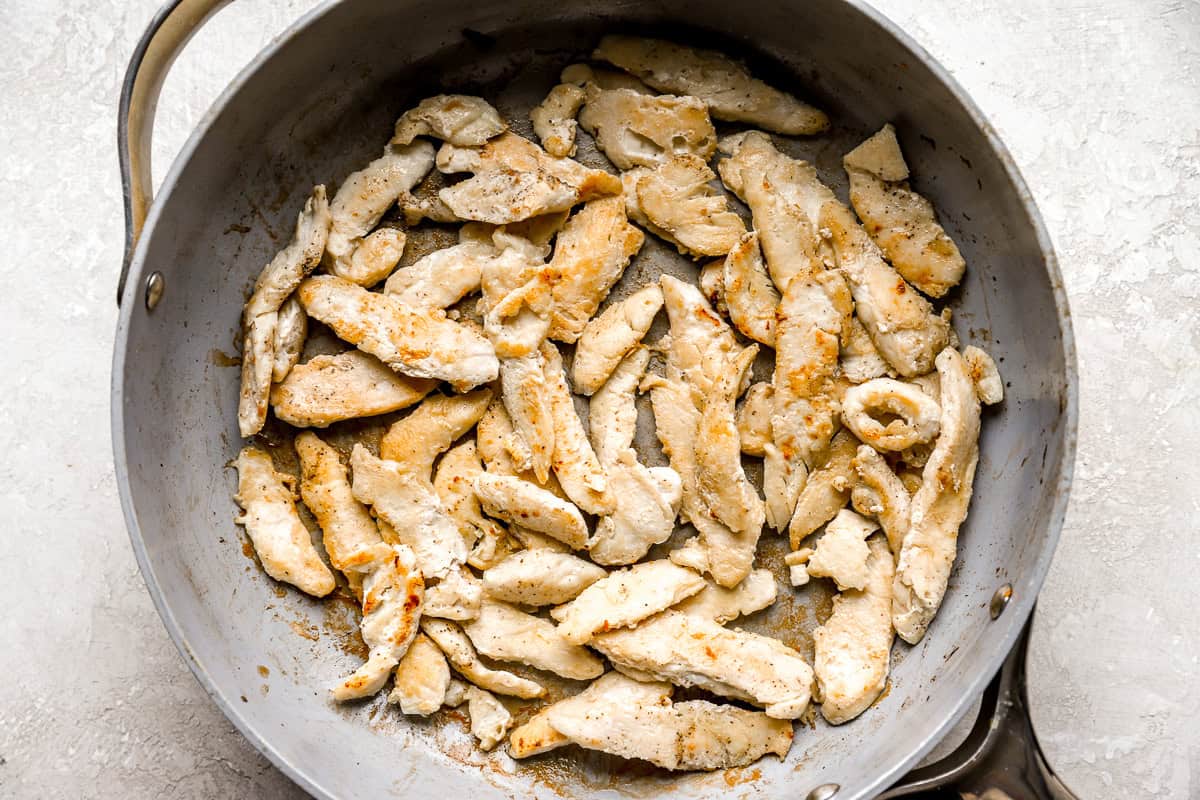 searing sliced chicken in a pan.