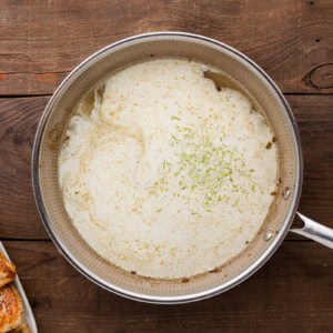 adding cream, lime juice, and lime zest to a skillet.