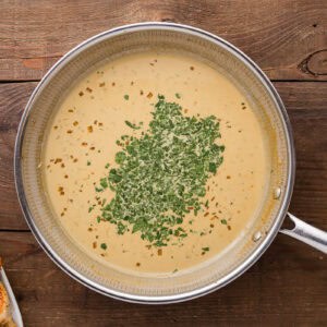 adding cilantro to lime cream sauce in a skillet.